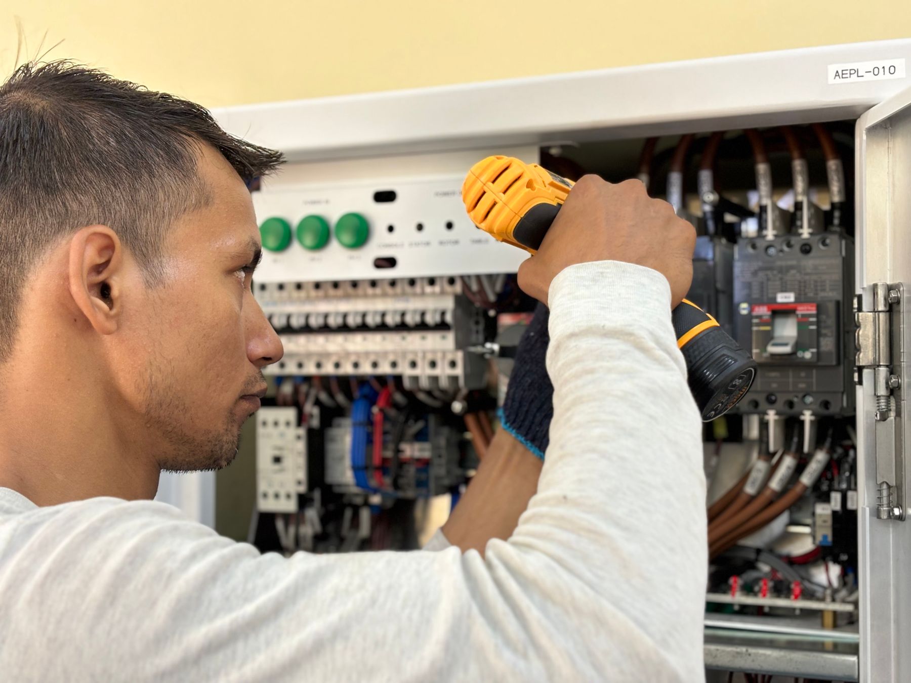 Electrician working on a distribution board with a drill