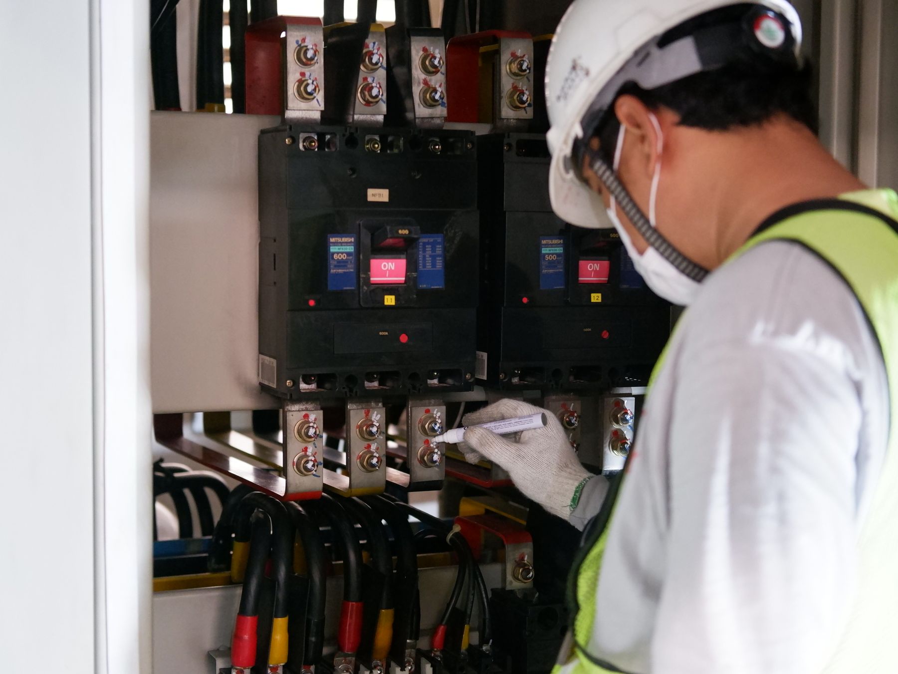 Electrician in a hard hat checking a power board